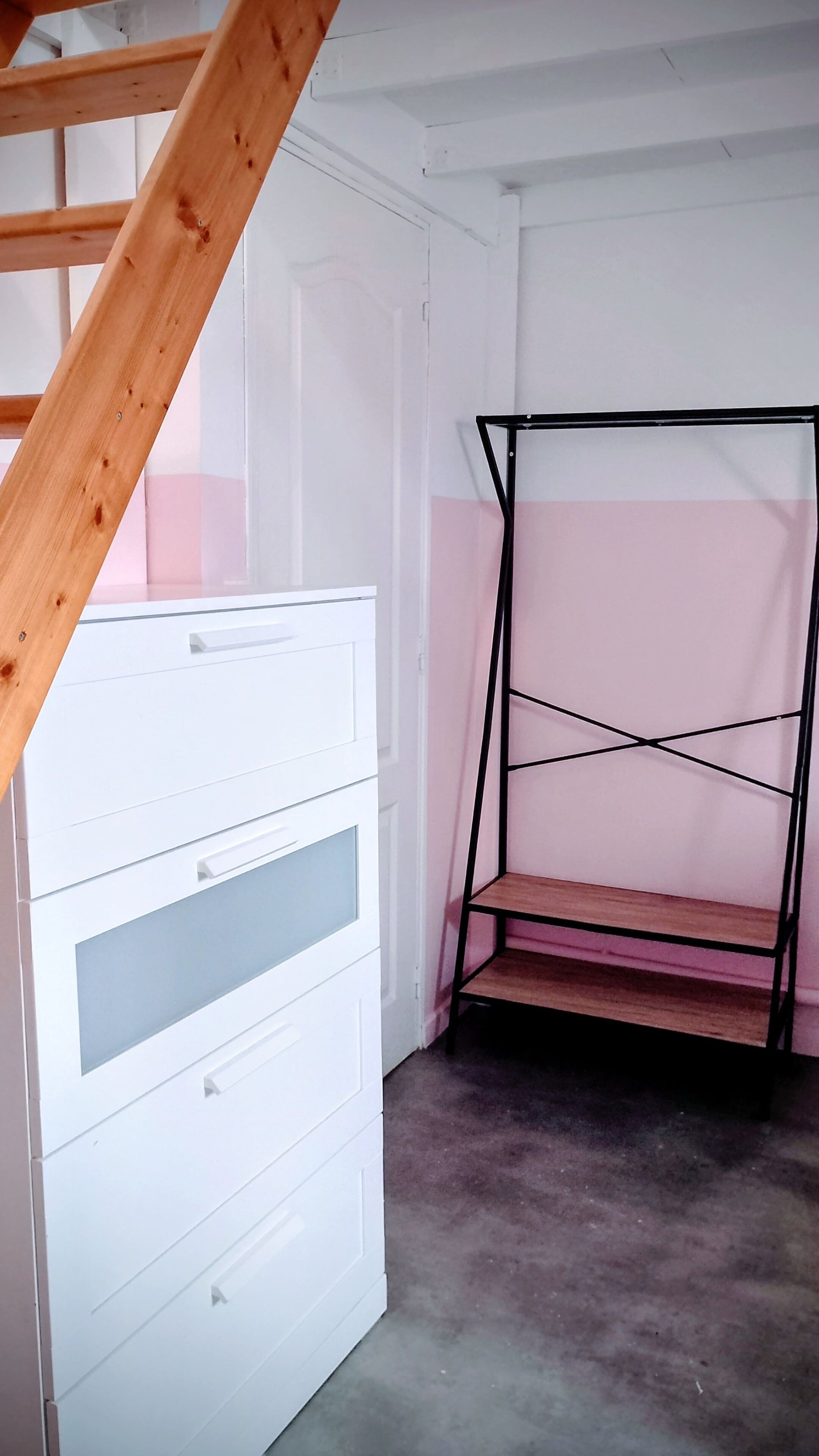 Een kamer met een witte dressoir, een zwart metalen plank en een houten trap.