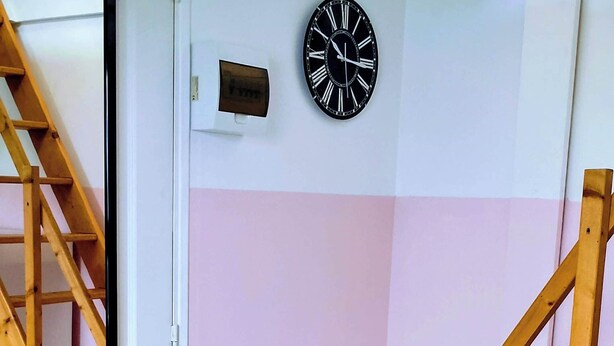A room with a wooden staircase, a white door, and a wall clock. - LES COMBLES DE PIERRE 6, Bollaert, Fac, 1pers, parking (Lens)