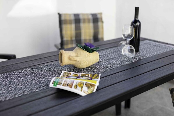 A table with a lace tablecloth, a wine bottle, a glass, and a decorative item.