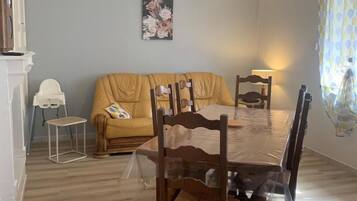 Un comedor con mesa de madera, sillas, un sofá, una mesita auxiliar y una lámpara colgante.