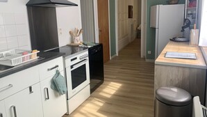 A kitchen with a stove, oven, dishwasher, and a trash bin. - Chez Mamie Gigi - DIENVILLE (DIENVILLE)