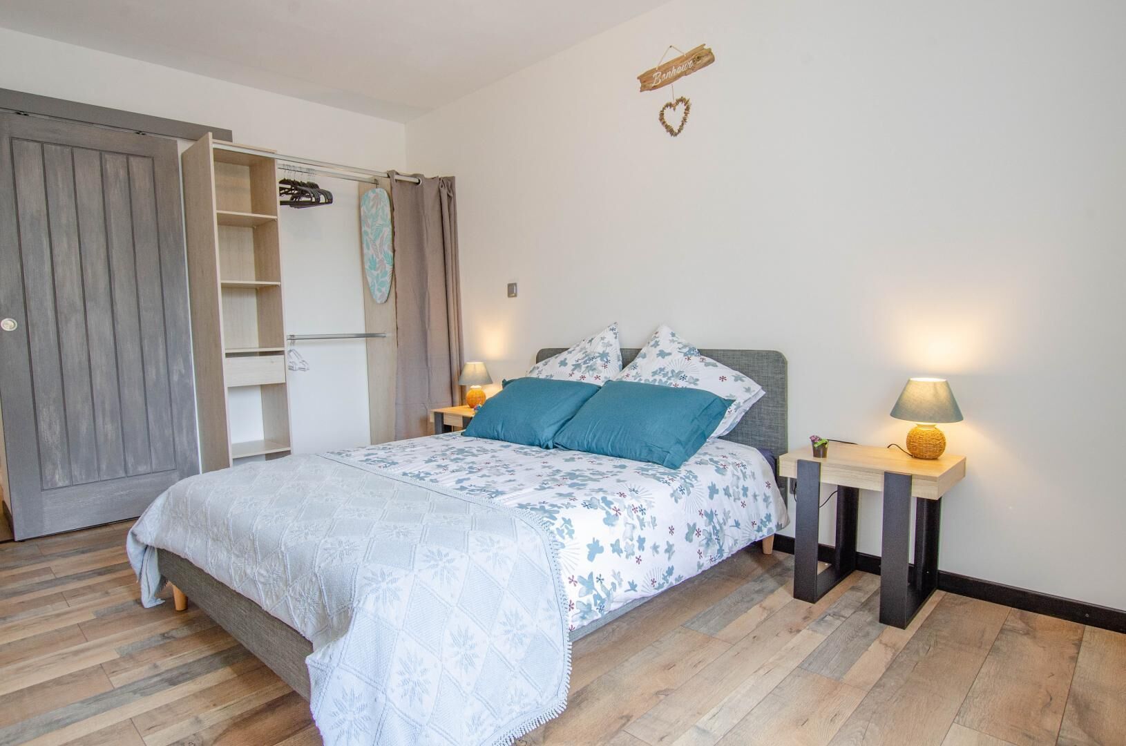 Une chambre à coucher comprenant un lit, des tables de chevet, une armoire et un élément décoratif mural.