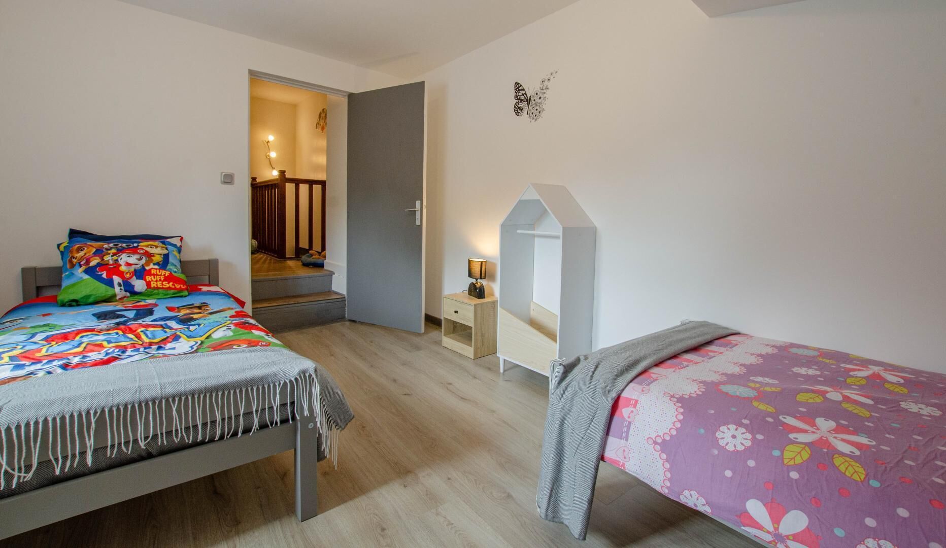Une chambre avec deux lits, une table de chevet, un miroir et un escalier menant à une salle de bain.