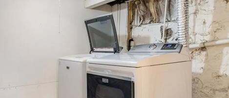 Une petite buanderie équipée d’un lave-linge, d’un sèche-linge et d’une poubelle.