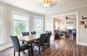 Un comedor amplio con mesa y sillas de madera, una sala de estar con sofá y mesa de centro, y un pasillo que conduce a otra habitación.