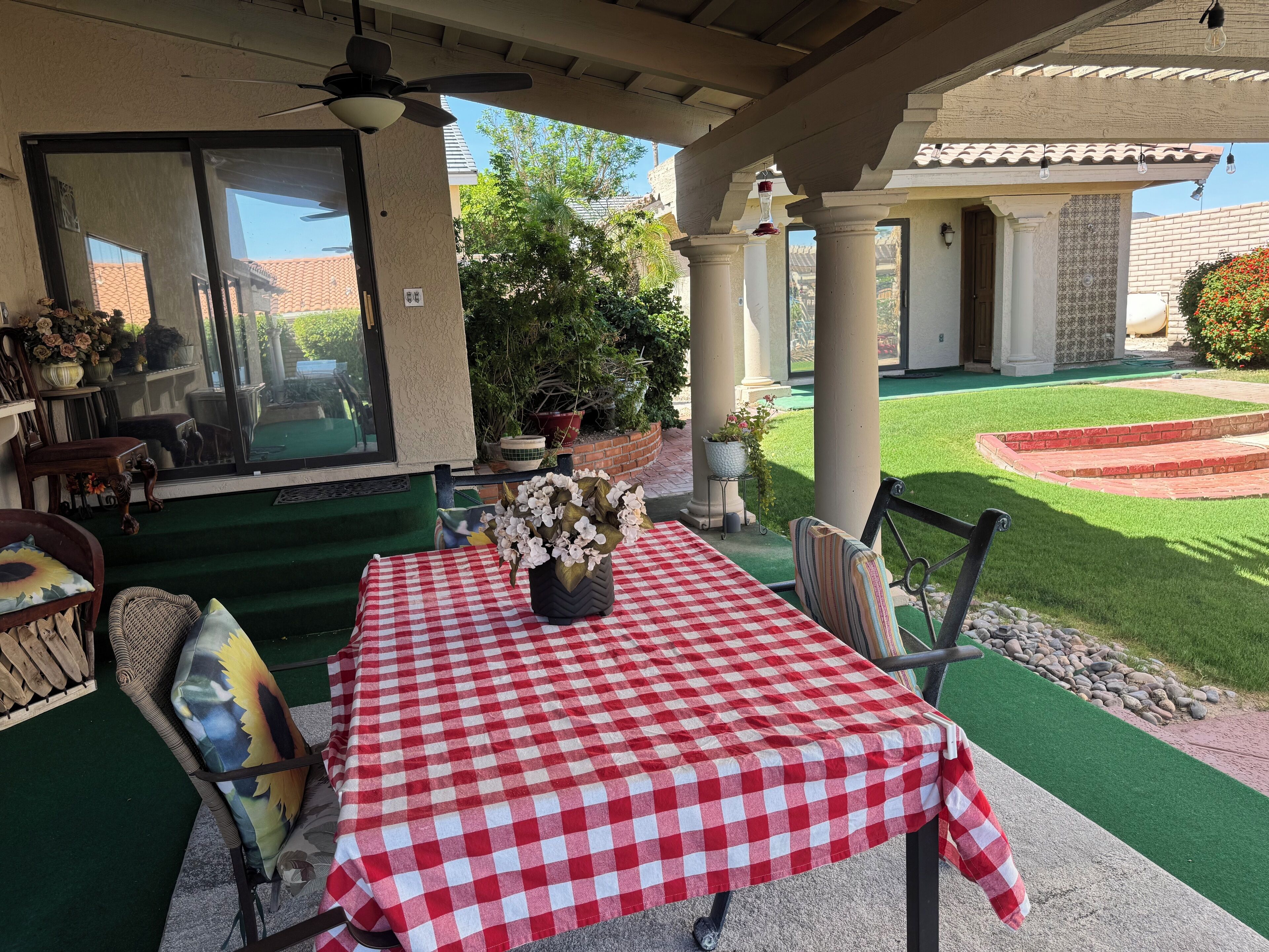 A patio with a checkered tablecloth, outdoor furniture, and potted plants.