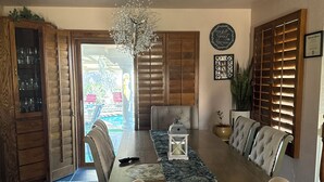 A dining area with a wooden table, upholstered chairs, a chandelier, and patterned rugs. - Beautiful Vacation Home with Pool (Yuma)