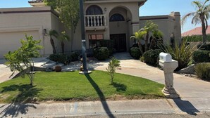 A two-story house with a red-tiled roof, a front entrance with a door, and a mailbox. - Beautiful Vacation Home with Pool (Yuma)