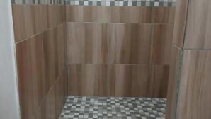 Una ducha con piso de cuadros y paneles de madera.