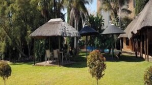 Un resort con construcciones de techo de paja, piscina y exuberante vegetación.
