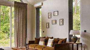 A spacious living room with a large window, a sofa set, a coffee table, and a rug.