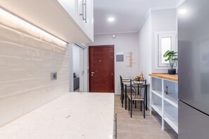 Eine moderne Küche mit Marmorarbeitsplatte, einer Holztür und einem Essbereich mit Stühlen und Tisch.