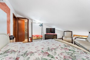 Un dormitorio con cama, televisor, silla y armario.