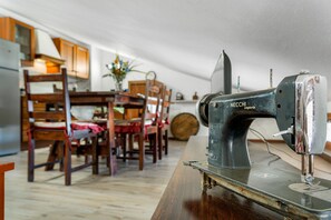 Una máquina de coser antigua sobre una mesa de madera en una habitación con muebles de madera y un comedor al fondo.