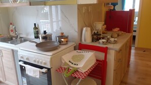 Een keuken met een kookplaat, gootsteen en diverse keukengerei.