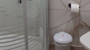 Een badkamer met een douchecabine van glas, een toilet en een wastafel.