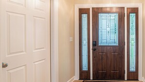 Un couloir avec un plancher en bois, une porte blanche et une porte marron avec une fenêtre.