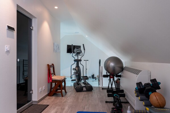 Une salle de sport à domicile équipée de matériel d’exercice, d’une chaise et d’un grand ballon de gymnastique.