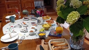 Une table de petit-déjeuner avec différents plats, un vase rempli de fleurs et une théière.