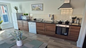 A modern kitchen with wooden cabinets, a white refrigerator, a microwave, and a stove. - Sandard Room In Town Centre (Middlesbrough)