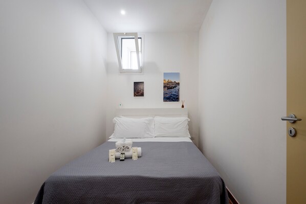 Un dormitorio con una cama, un ventanal y dos cuadros colgados en la pared.