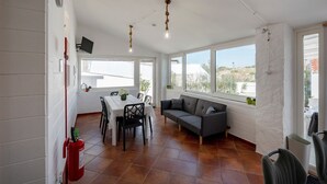 Amplia habitación con mesa de comedor, sillas, sofá y grandes ventanales que ofrecen vistas.