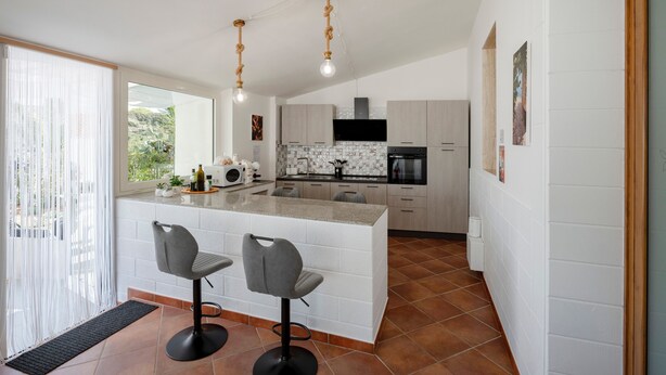 Una cocina moderna con una isla central, taburetes de bar e iluminación colgante.