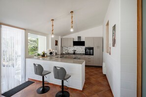 A modern kitchen with a central island, bar stools, and pendant lights.