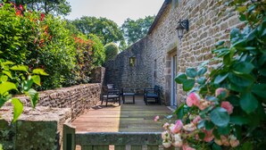 A stone building with a wooden deck, outdoor seating, and a stone wall.