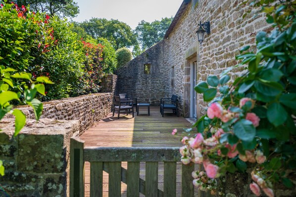 A stone building with a wooden deck, outdoor seating, and a stone wall.