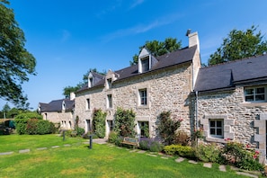 A stone building with multiple windows and a well-maintained garden.