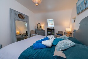 Un dormitorio con una cama grande, un aparador, un espejo, una estantería y una ventana.