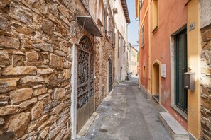 Une ruelle étroite aux murs de pierre, donnant sur une rue également étroite.