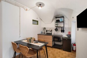 Une cuisine compacte comprenant un coin repas, un petit réfrigérateur et un extincteur.