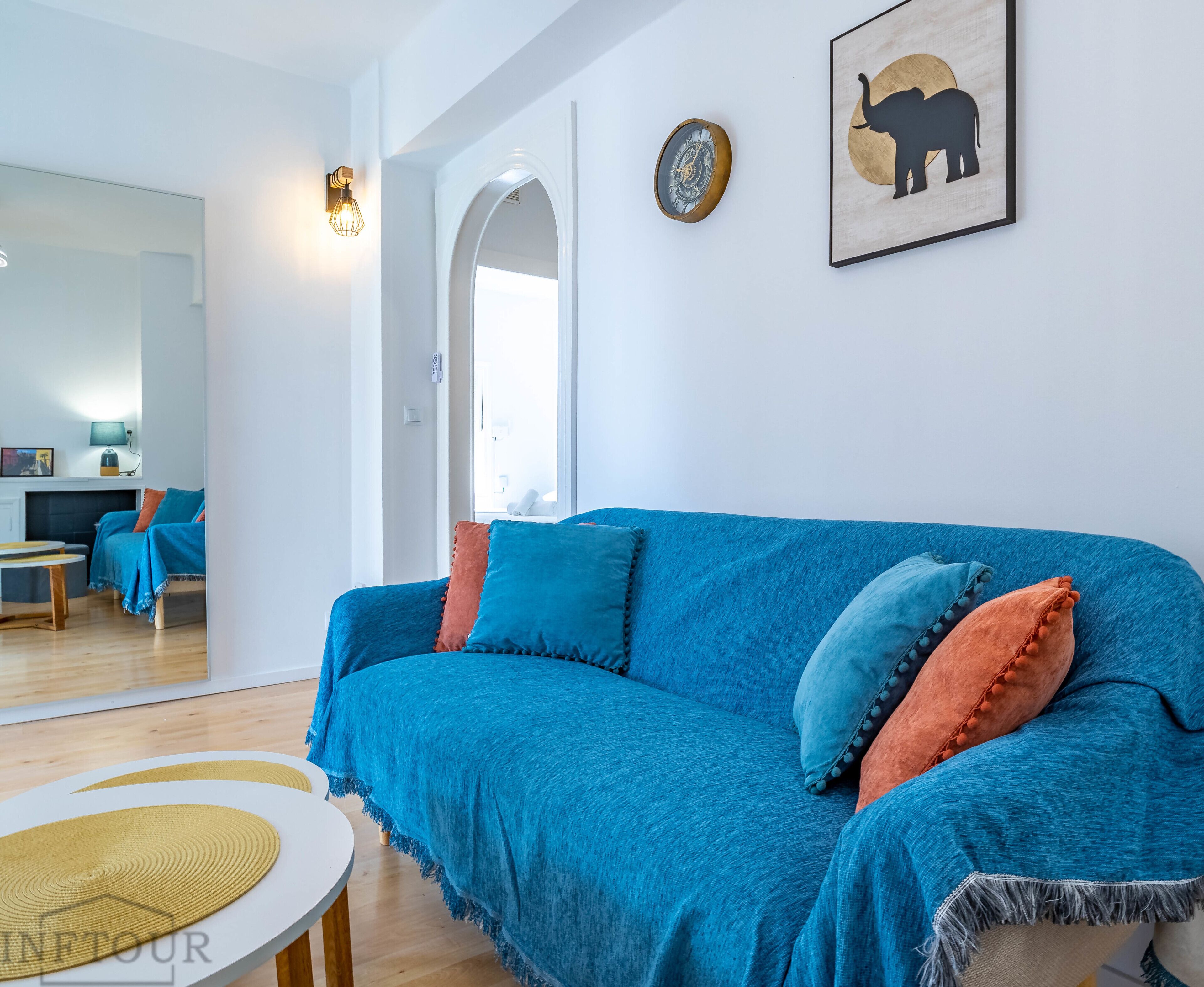 A modern living room with a blue sofa, a round coffee table, and a framed elephant artwork on the wall.
