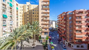 A multi-story residential building with balconies, a street in front, and palm trees. - Inftour Garvimar Apartamento (Calp)