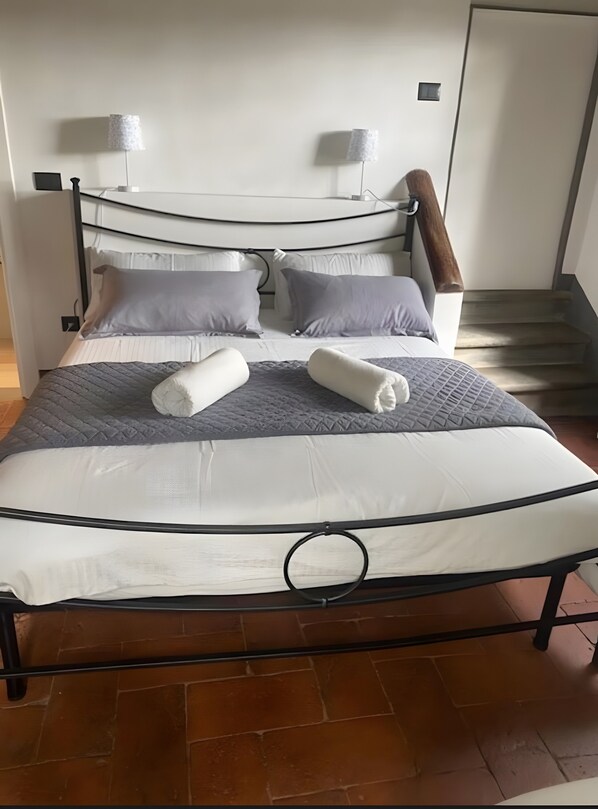 Una cama bien hecha con cabecera, almohadas y manta.