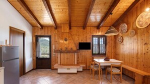 Interior de madera con cocina, una mesa de comedor y televisor.