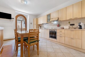 Une cuisine moderne avec des meubles en bois, un four encastré et un coin repas comprenant une table et des chaises.