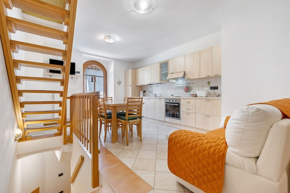 Une cuisine moderne avec des meubles en bois, un coin repas comprenant une table et des chaises, et un escalier doté d’une rampe en bois.