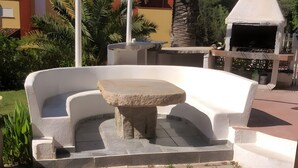 A courtyard with a stone fountain, a barbecue grill, and a paved area. - Double Room 'Matrimoniale Vicino Al Mare' with Sea View, Shared Pool and Shared Terrace (Platamona)