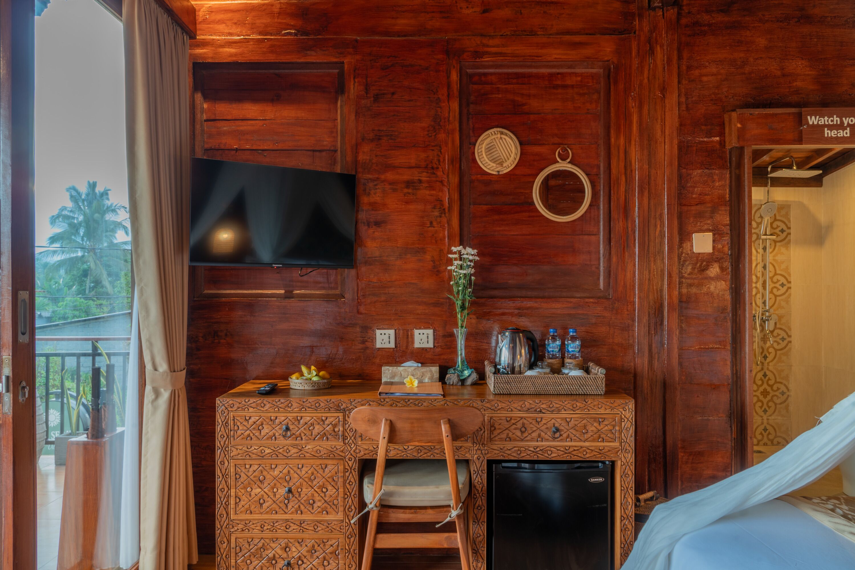 Um quarto de madeira com cama, escrivaninha e televisão.