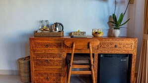 A wooden desk with drawers, a chair, a small refrigerator, and a potted plant. - Tiara Villa Ubud by Dhananjaya Hospitality (Sebatu)