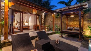 A cozy outdoor seating area with wicker furniture, a covered patio, and a private bedroom with a canopy bed. - Tiara Villa Ubud by Dhananjaya Hospitality (Sebatu)