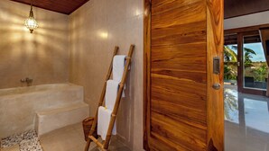 A modern bathroom with a wooden door, a bathtub, and a shower area. - Tiara Villa Ubud by Dhananjaya Hospitality (Sebatu)