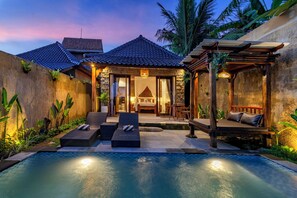 A poolside area with lounge chairs, a covered seating area, and a bedroom with a bed and curtains. - Tiara Villa Ubud by Dhananjaya Hospitality (Sebatu)