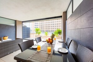 A dining area with a table set for two, a fruit bowl, and two glasses of orange juice. - Sofie Seaview Apartment – Beachfront, Family-Friendly, with Pools and Gym (Roquetas de Mar)