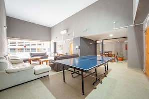 Una sala de estar moderna con mesa de ping pong, paredes grises y un sofá.