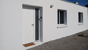Un edificio moderno con fachada blanca, una puerta y dos ventanas.