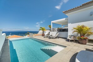 Ein Pool auf dem Dach mit Blick auf den Ozean, Liegestühle und Kübelpflanzen.